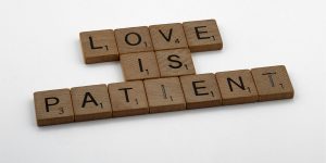 An image of Scrabble tiles spelling the phrase "Love is patient."