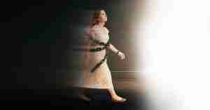 Image of a woman walking from darkness toward light as chains fall off her body.