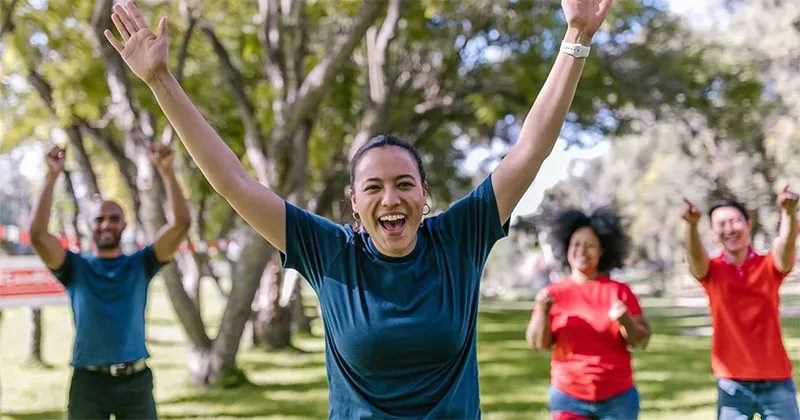Group of people outside stretching and smiling.
