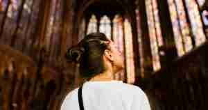 Young woman in Gothic church looking up at windows.