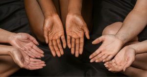 A circle of hands with their palms up.